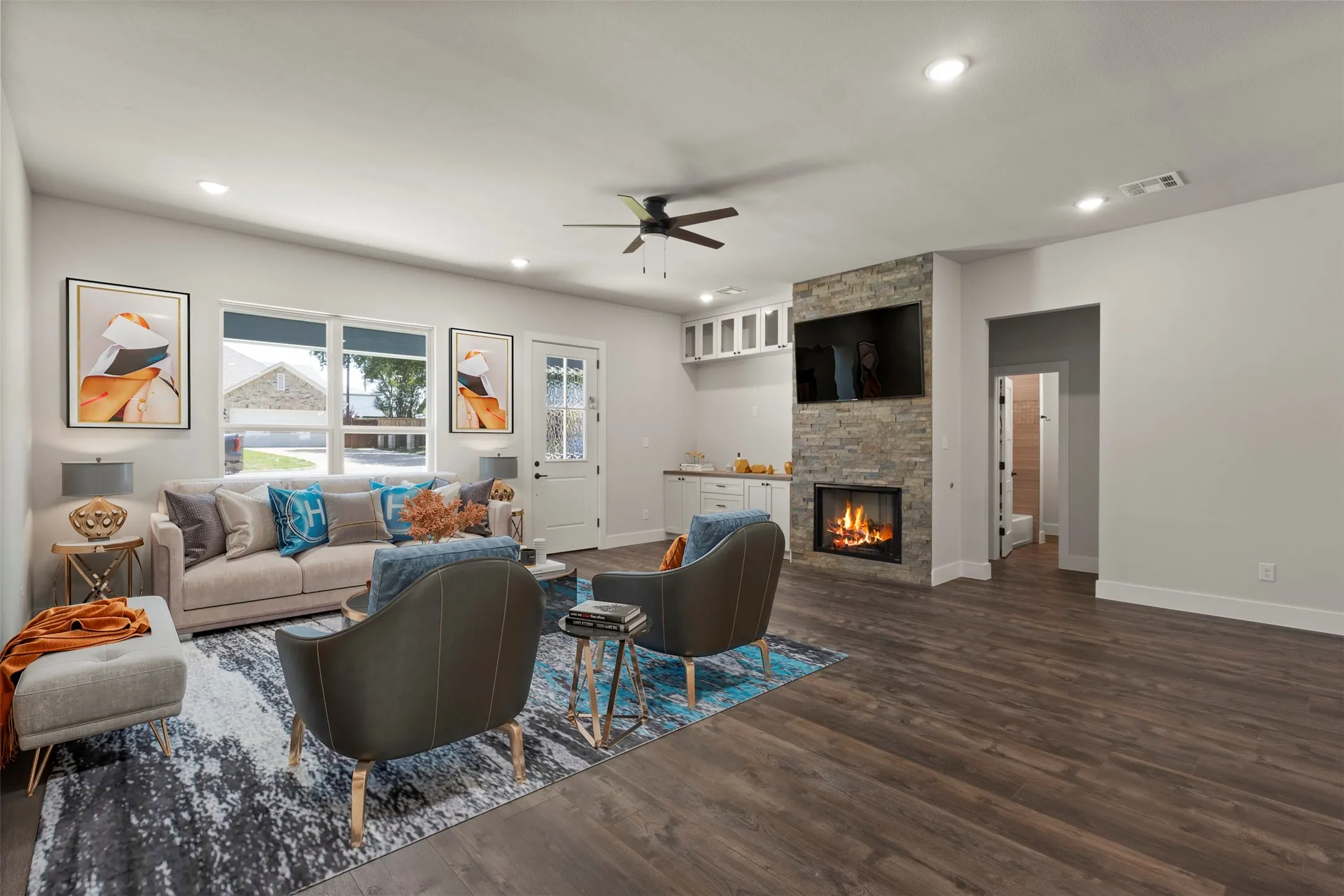 Spacious living area featuring wood-finish flooring, a stone-clad fireplace, recessed lighting, and a ceiling fan