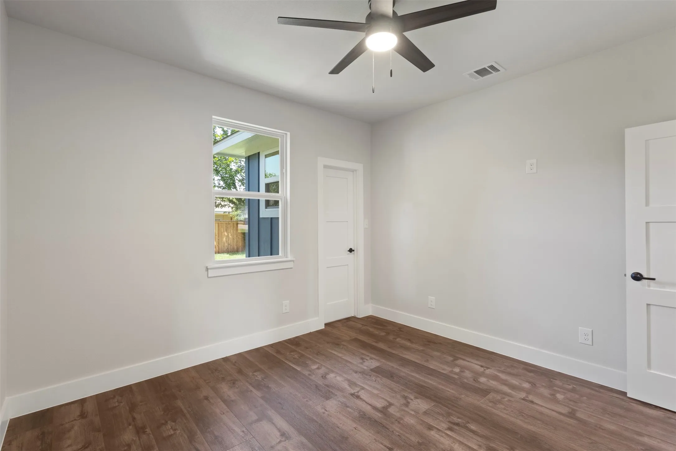 Bedroom featuring wood-finish flooring, light gray walls, white trim, a single window, and a ceiling fan with integrated​​‌​​​​‌​​‌‌​‌‌​​​‌‌​‌​‌​‌​​​‌​​ lighting