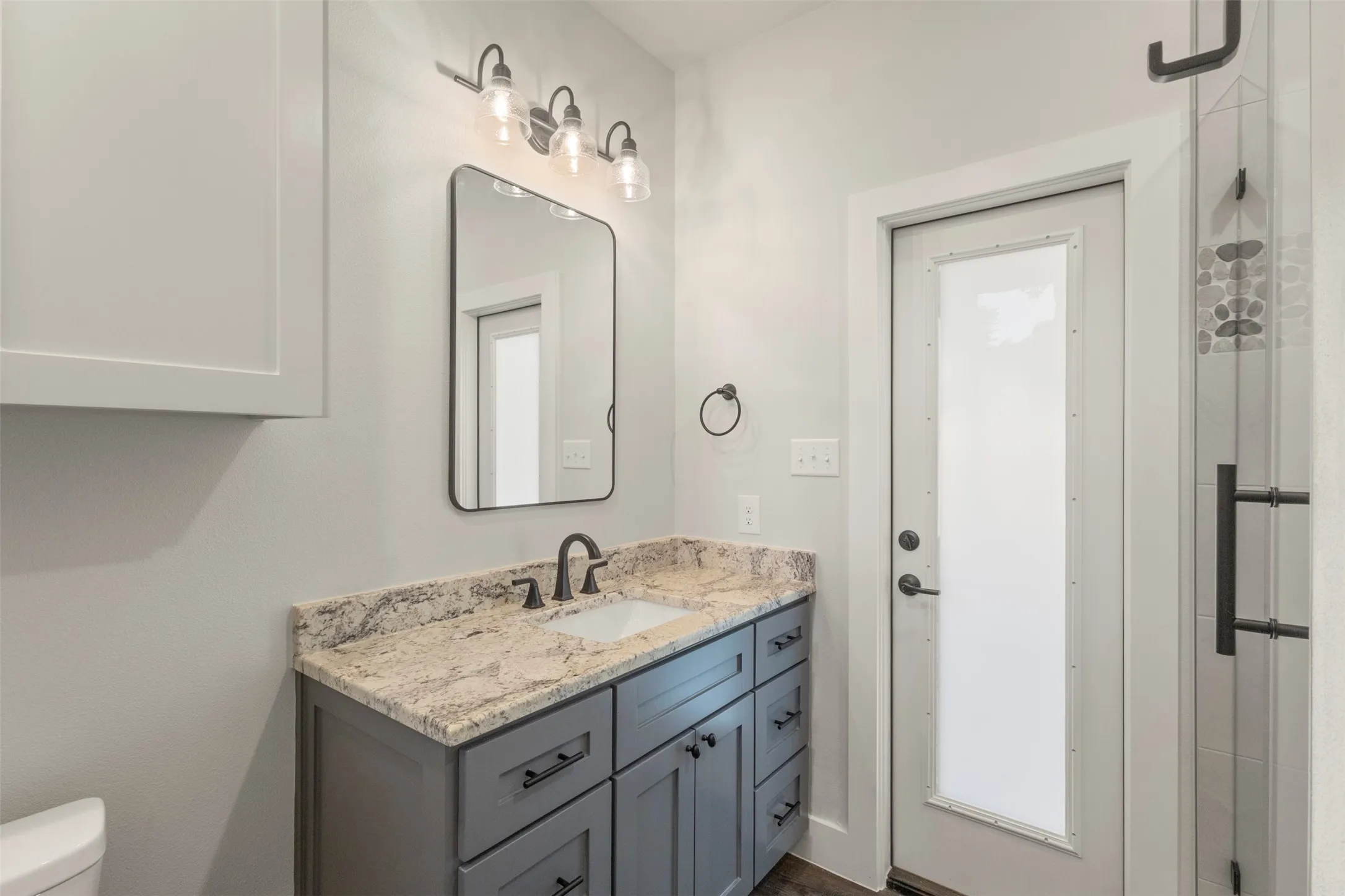 Vanity featuring a stone countertop with an undermount sink, dark gray cabinetry, and matte black fixtures