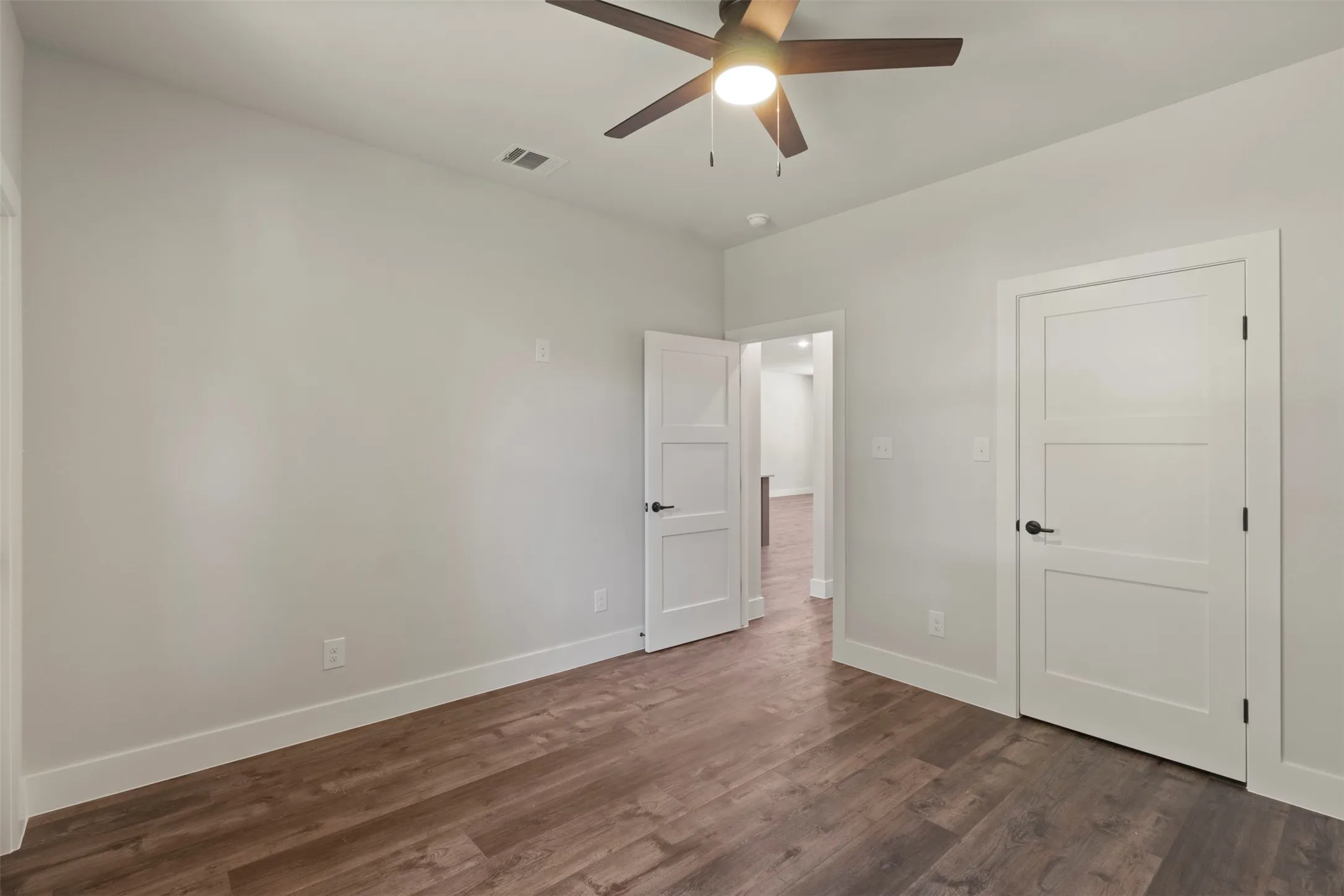 Interior room featuring wood-finish flooring, light gray wall paint, and white baseboards