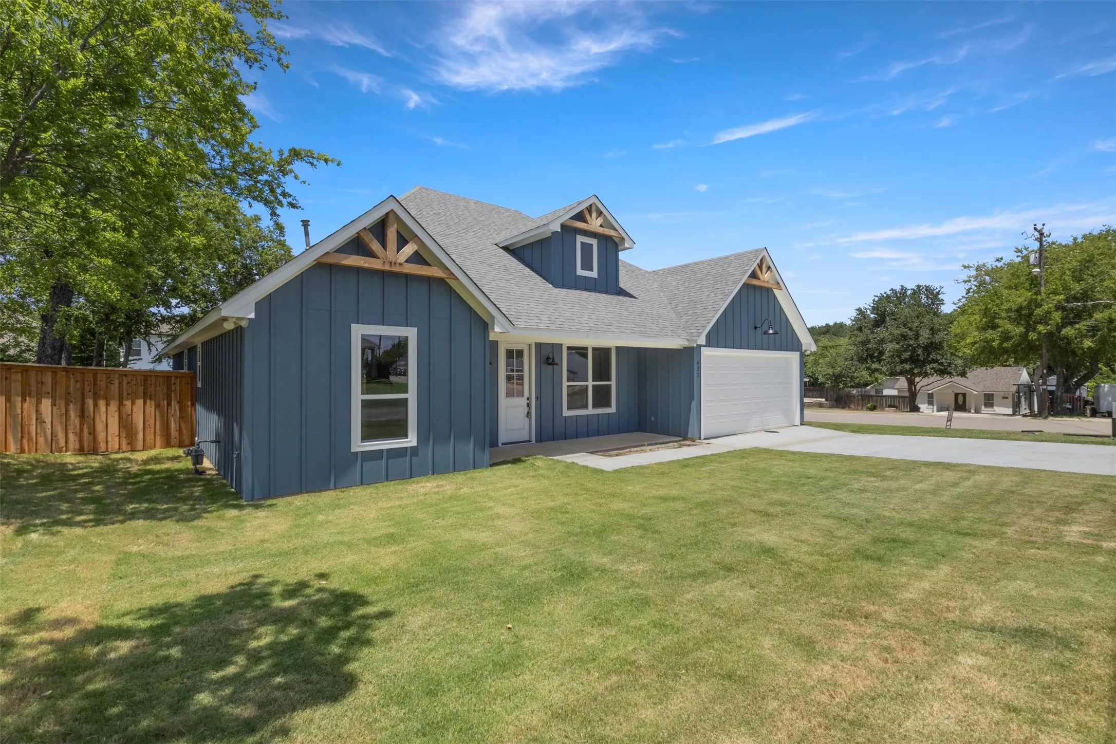 Modern farmhouse exterior with blue board and batten siding, white trim, a light gray asphalt shingle roof, a two-car garage, and a concrete driveway