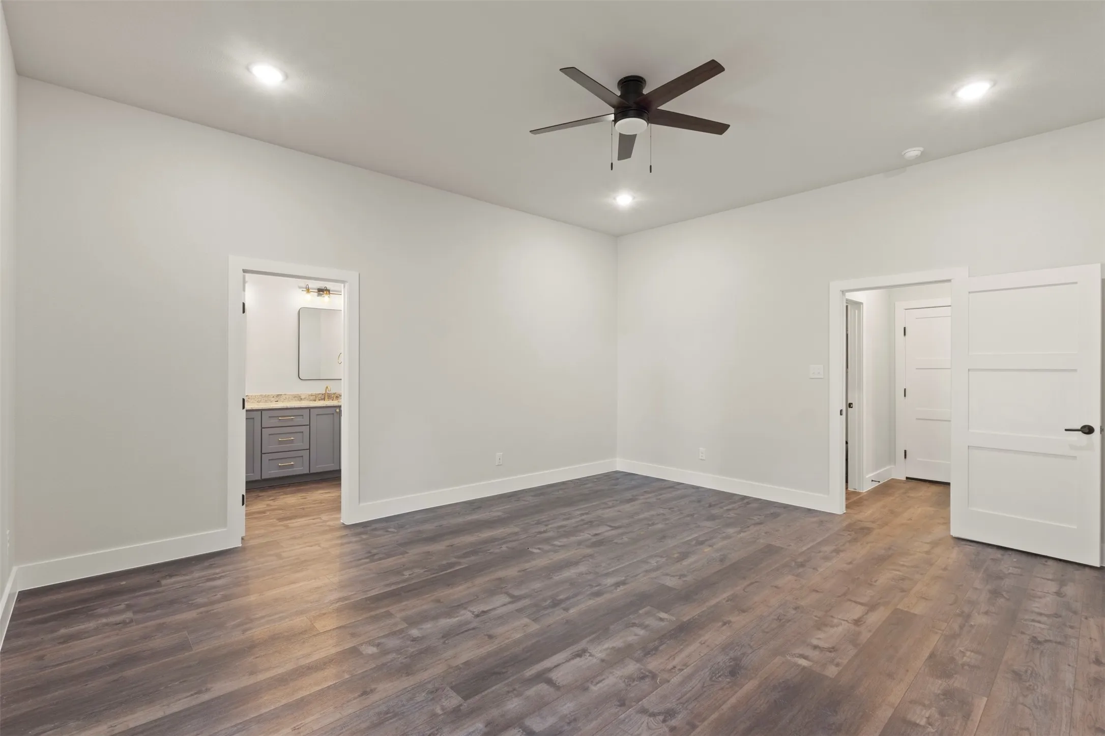 Spacious room featuring wood-finish flooring, recessed lighting, and a ceiling fan