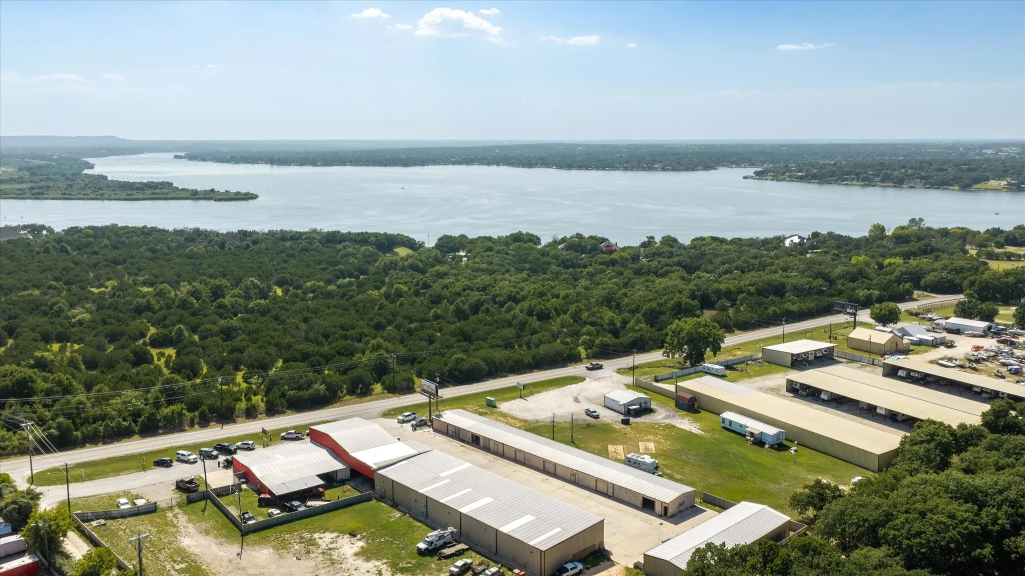 Aerial perspective showcasing a large body of water bordered by dense tree coverage and commercial structures
