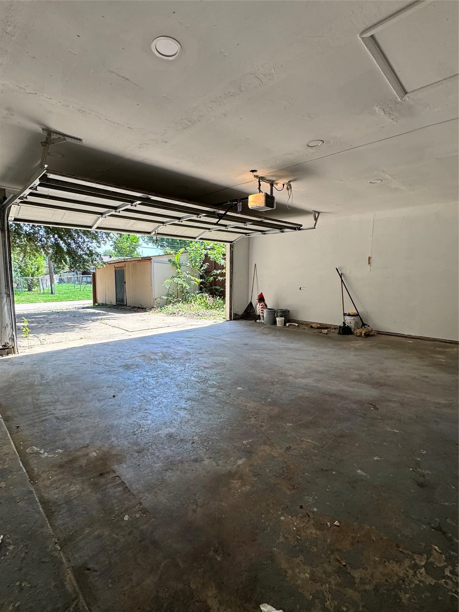 Spacious garage featuring a concrete floor, an overhead garage door, a garage door opener, and ceiling-mounted recessed lighting