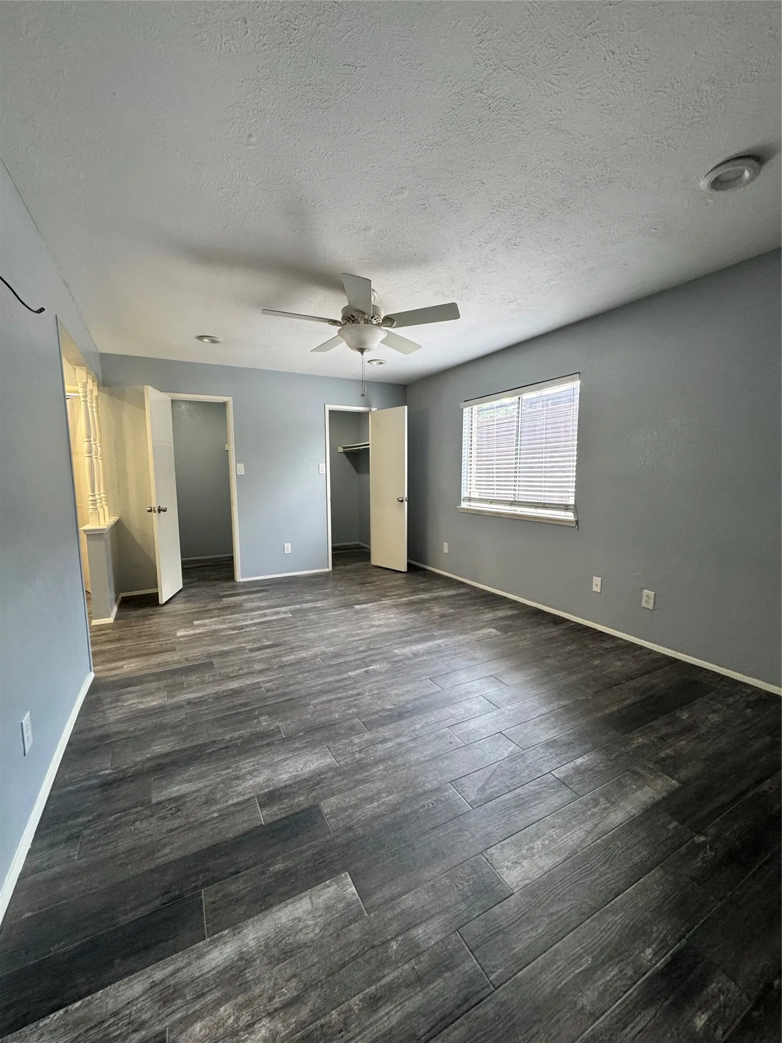 Spacious room featuring wood-finish flooring, ceiling fan, recessed lighting, and a window with blinds