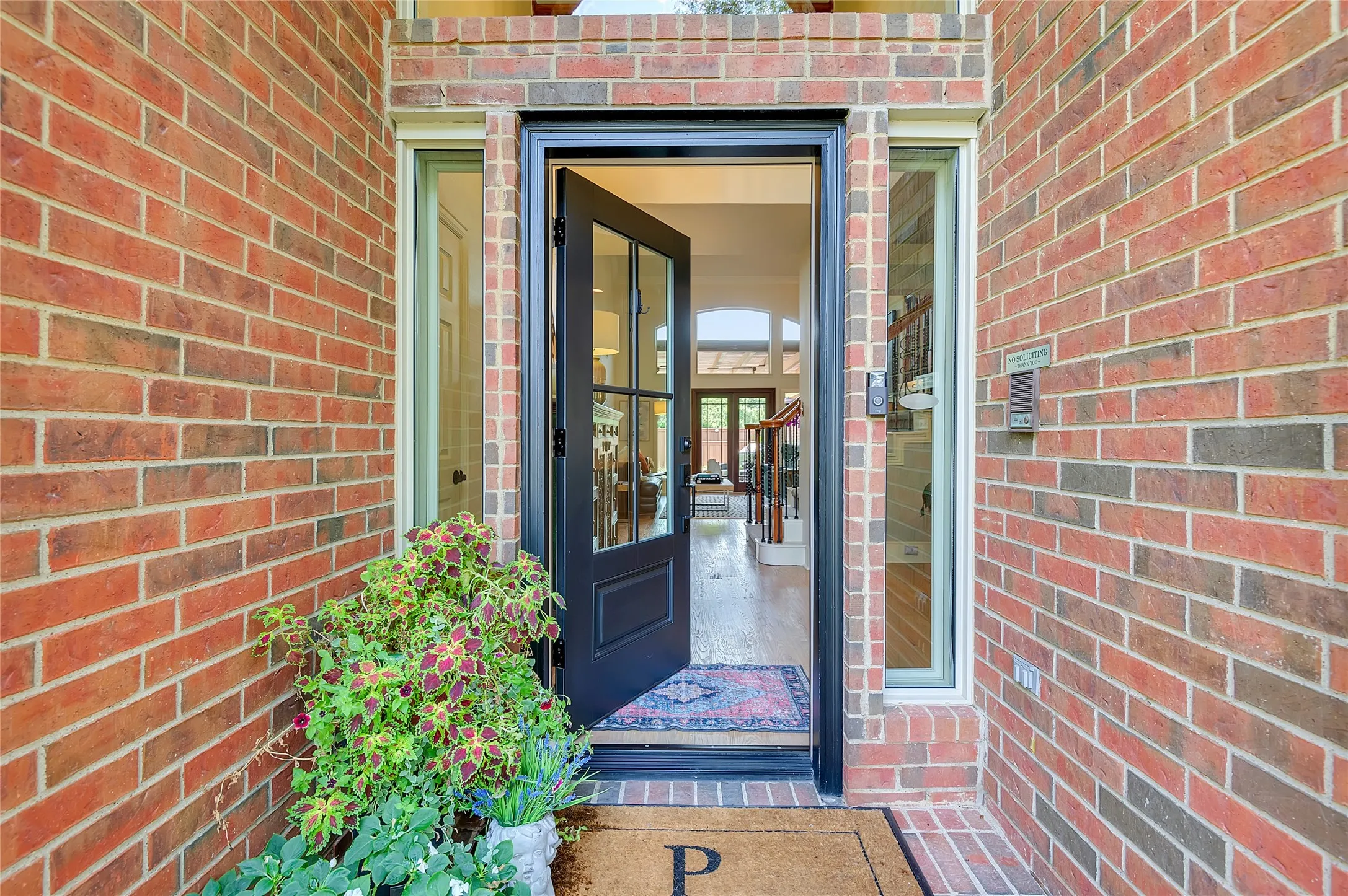 Brick facade featuring a glass-paneled entry door, sidelight windows, and a hardwood-finish interior