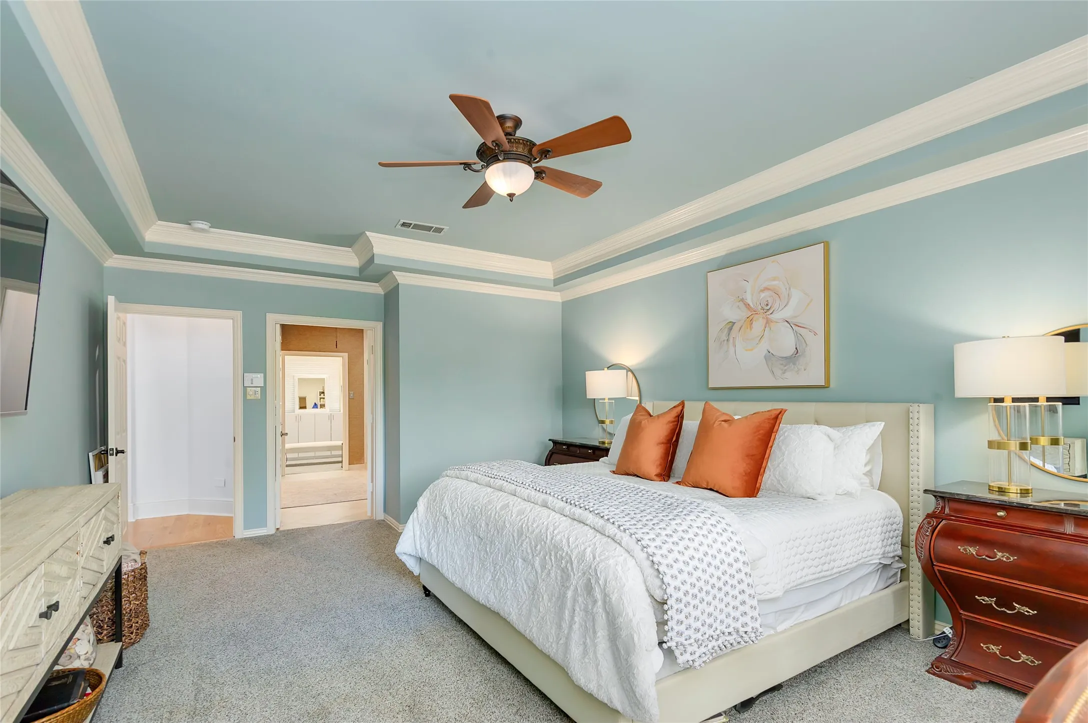 Bedroom featuring a tray ceiling with crown molding, a ceiling fan with integrated lighting, and plush carpet flooring