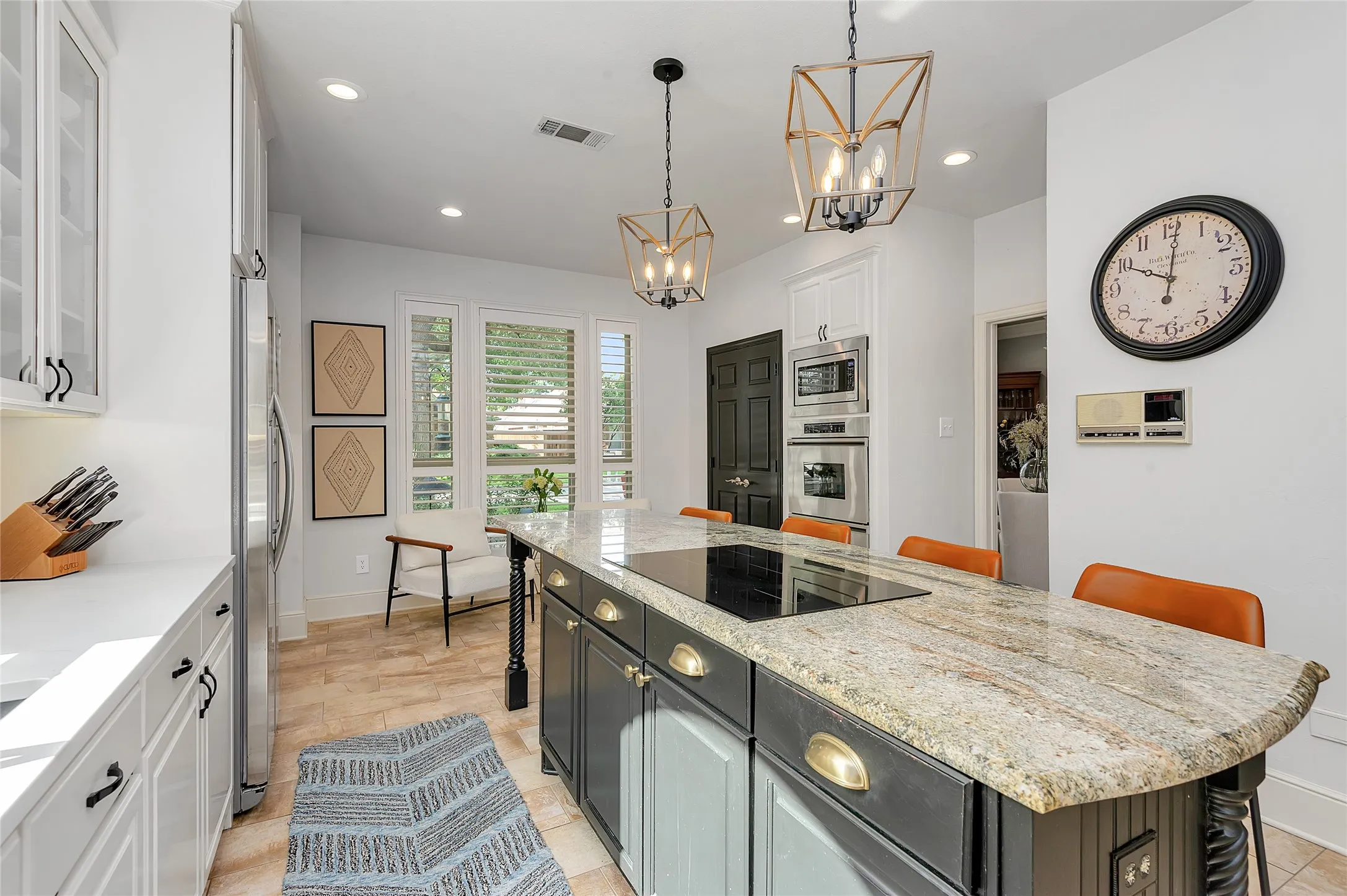 Expansive kitchen island with a built-in cooktop and granite countertop, framed by three pendant light fixtures