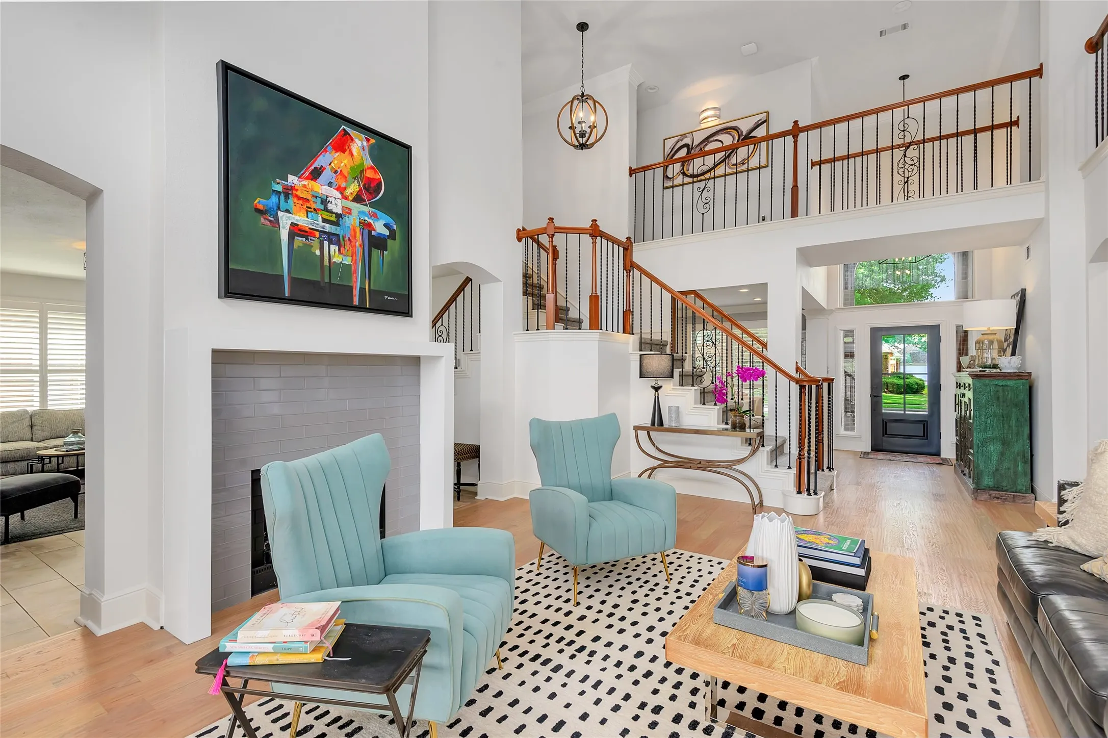 Grand entry foyer featuring a two-story ceiling, light wood-finish flooring, and a prominent staircase with wood handrails and wrought iron balusters