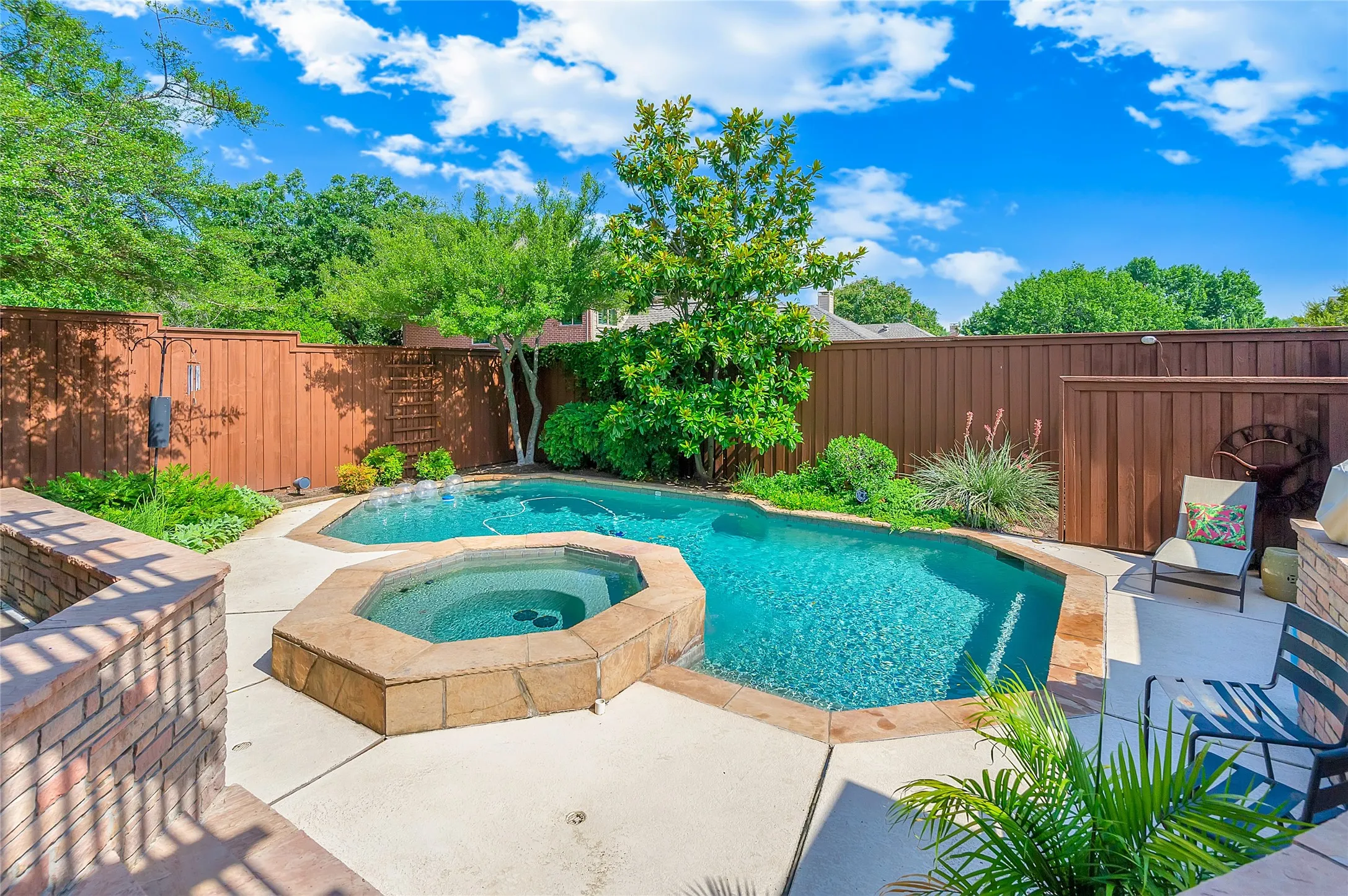 Private backyard oasis featuring a freeform swimming pool and an octagonal spa, both with stone coping