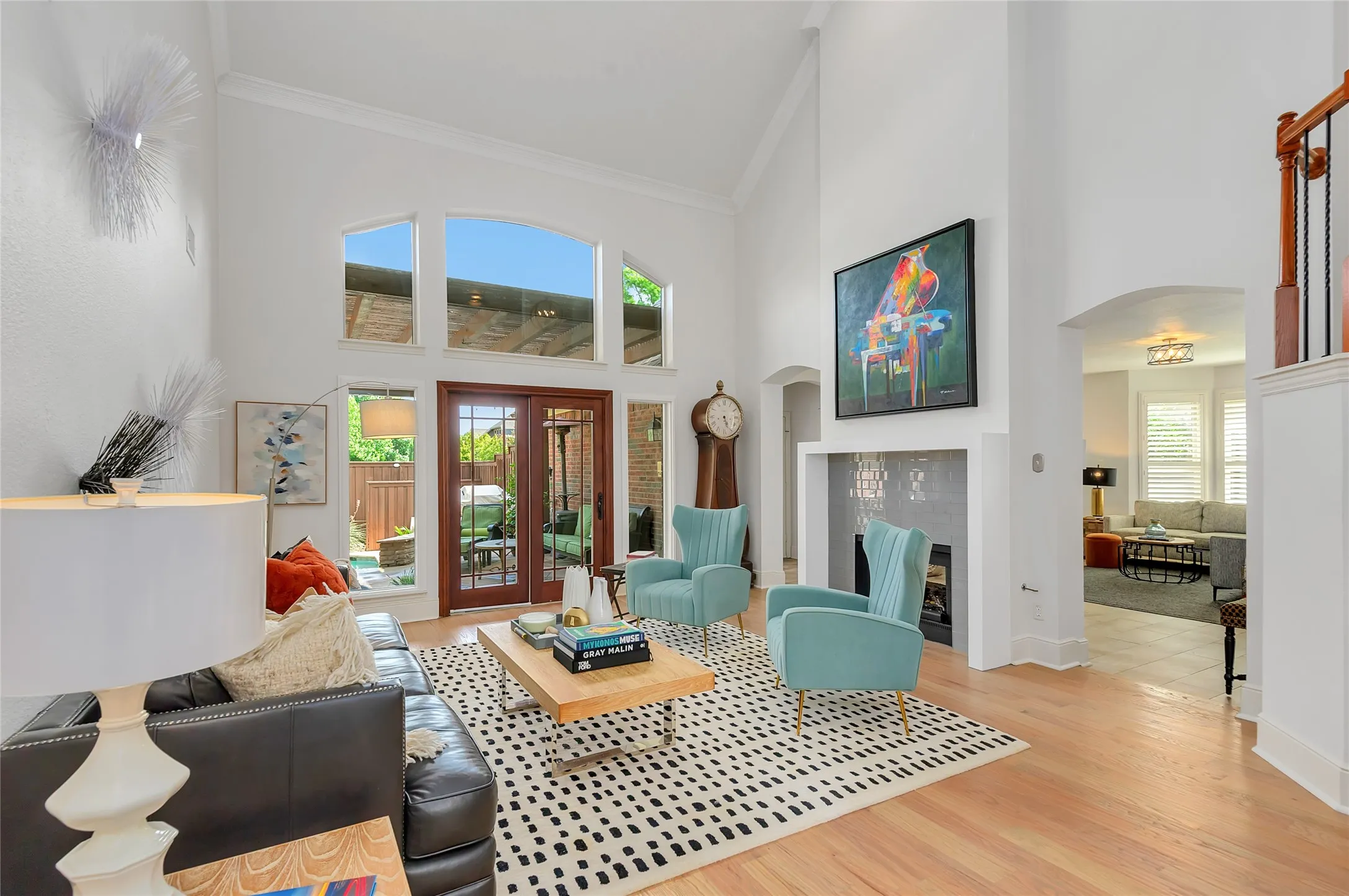 Living area featuring high vaulted ceilings, wood-finish flooring, a fireplace with tile surround, and expansive windows