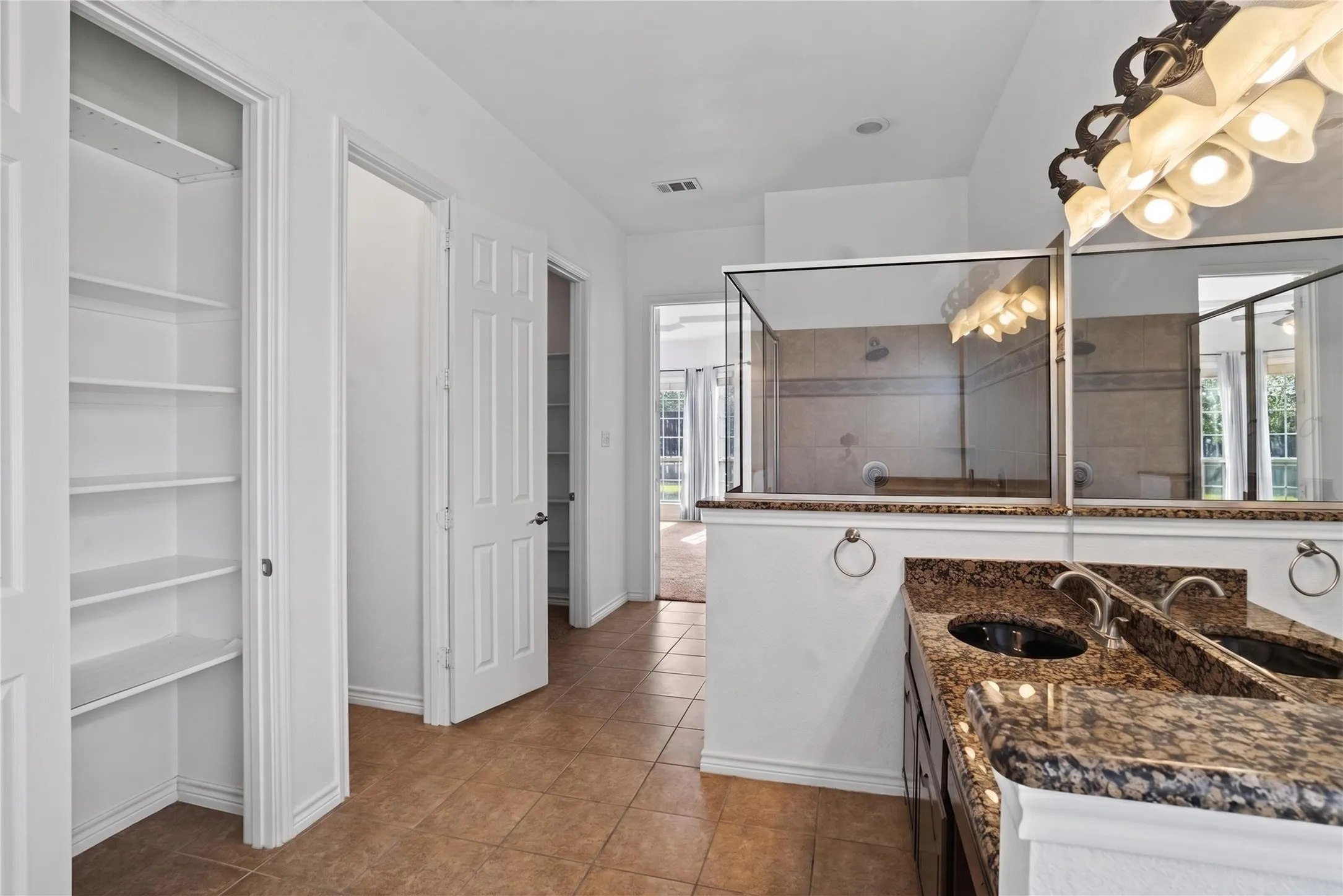 Big size primary bathroom with stand alone shower area with a bench and dual shower heads.