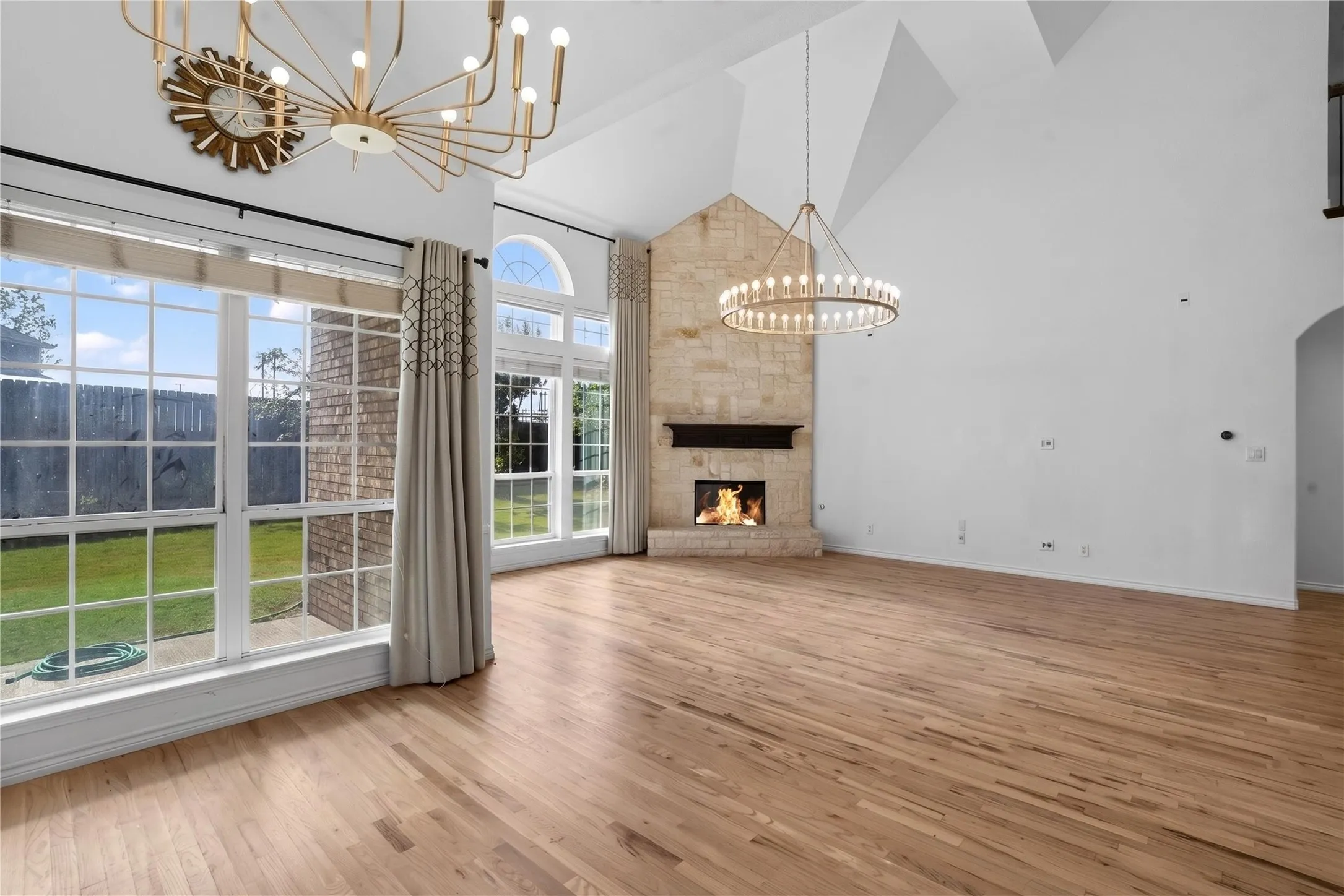 Oversized living room space with High vaulted ceiling, floor to ceiling windows flooding the space with natural light! Check out the custom chandeliers setting a luxurious tone from the moment you step inside!