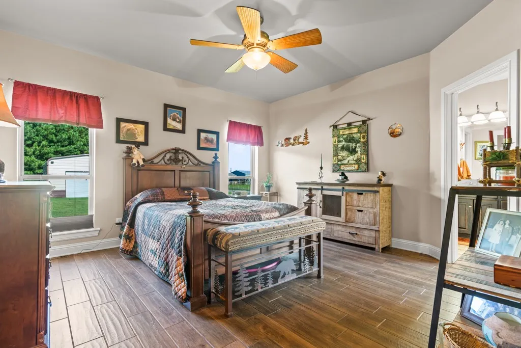 Spacious room with wood-finish flooring, two large windows, and a ceiling fan