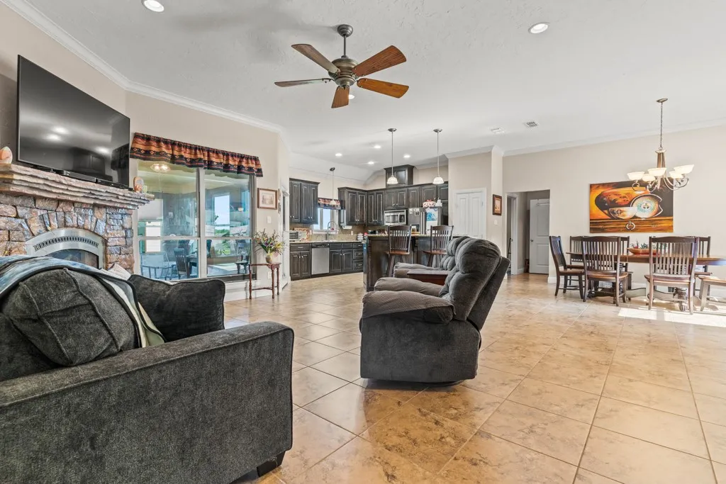 Spacious living area featuring a floor-to-ceiling stone fireplace, ceiling fan, recessed lighting, and tile flooring