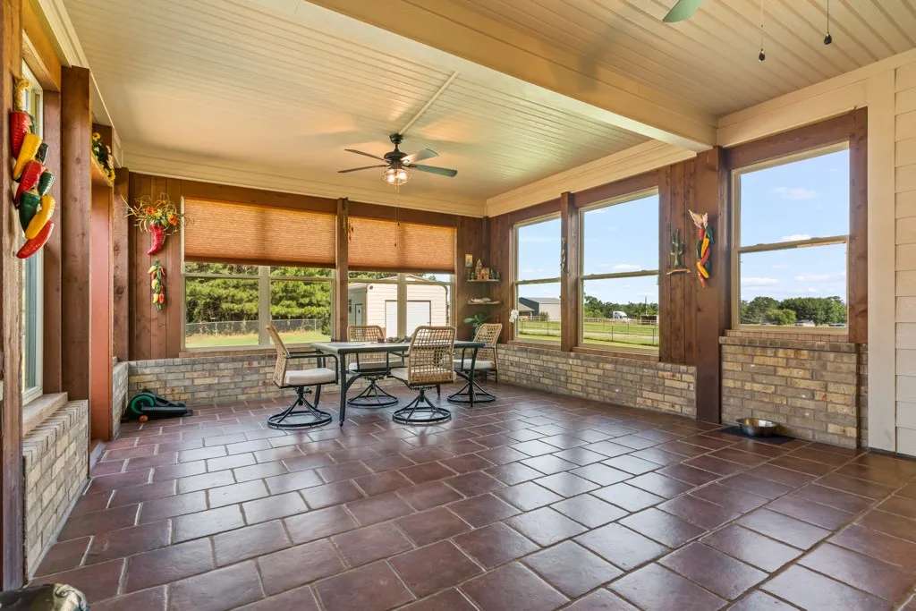 Screened porch featuring extensive brick wainscoting, wood-paneled walls, and a wood-finish plank ceiling