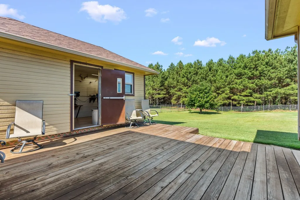 Expansive wood deck with a durable surface, offering direct access to a large grass area