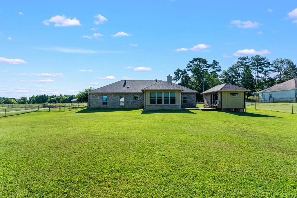 Expansive green lawn with a single-story brick and siding residence featuring a covered patio