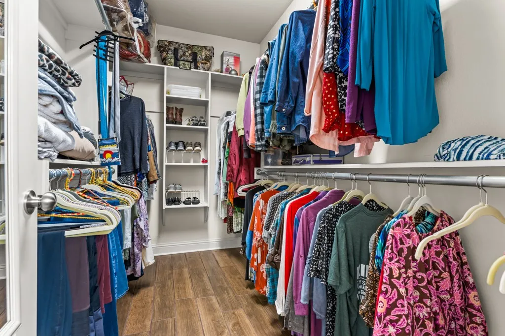 Walk-in closet featuring wood-finish flooring, white shelving, multiple hanging rods, and recessed lighting