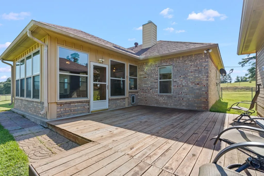 Expansive wood deck with a partial brick facade, large windows, and an exterior door