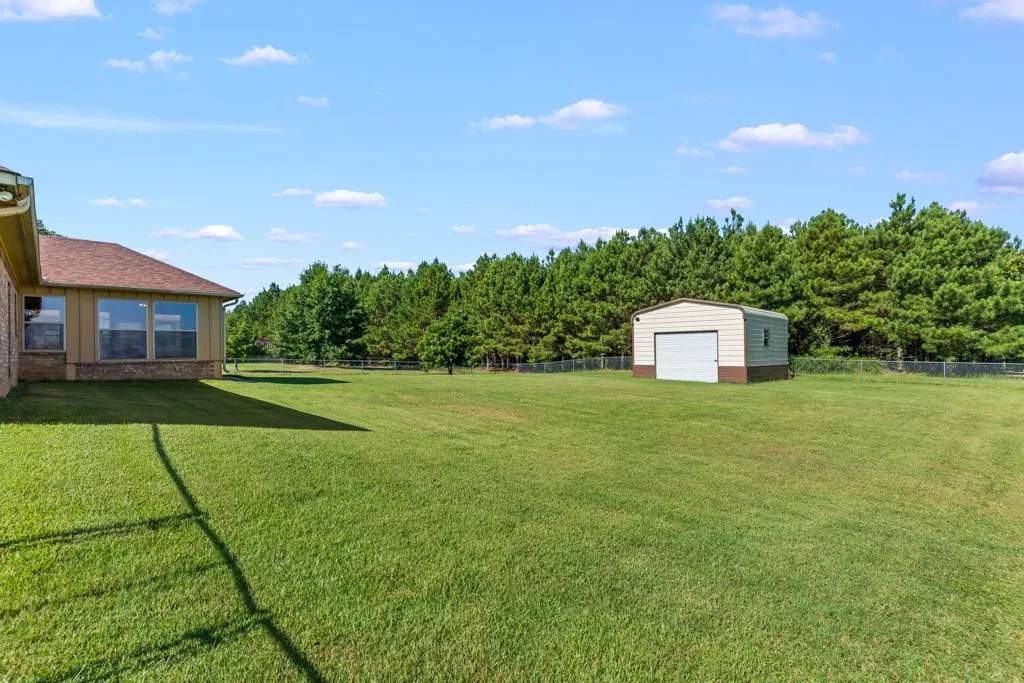 Expansive green lawn with a detached metal outbuilding featuring a white roll-up door