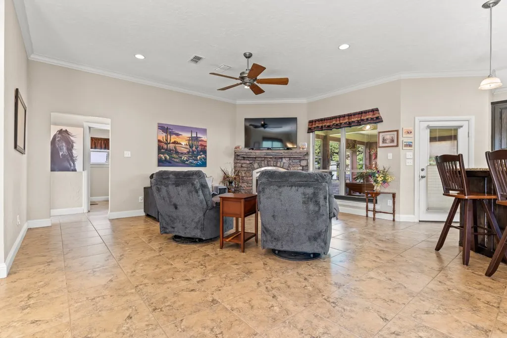 Spacious common area featuring neutral wall tones, crown molding, recessed lighting, and a ceiling fan