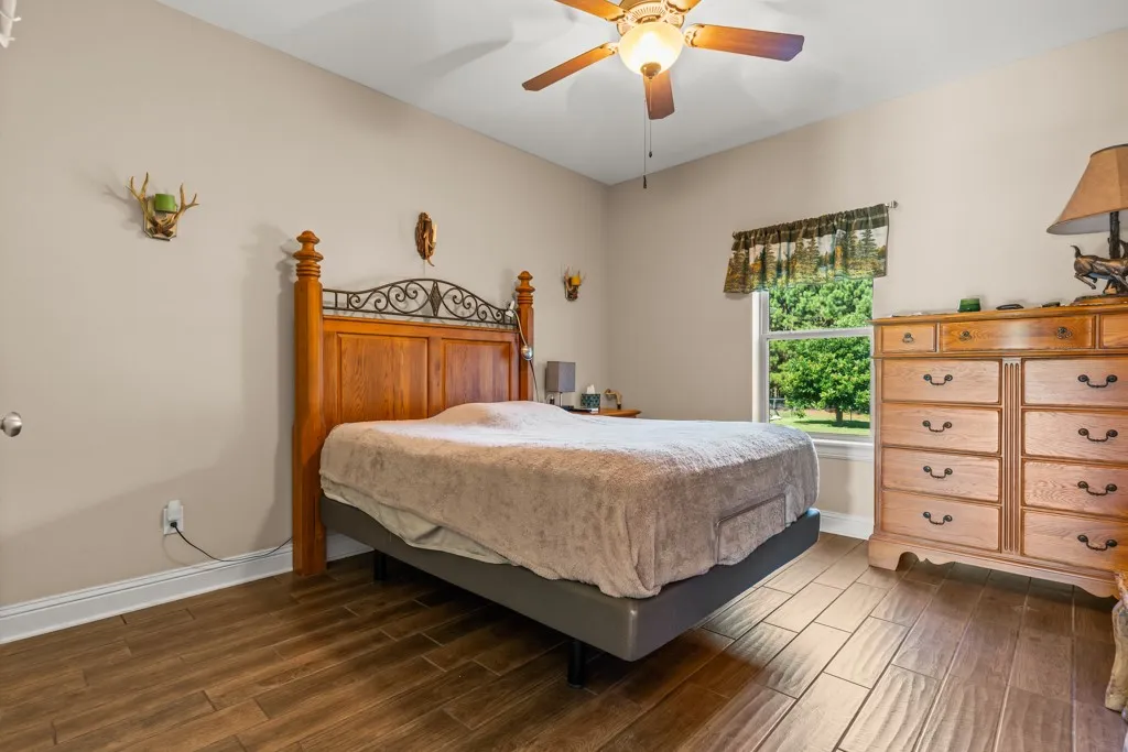 Interior room featuring wood-finish flooring, a window providing natural light, a ceiling fan with integrated lighting, and neutral-toned wall paint