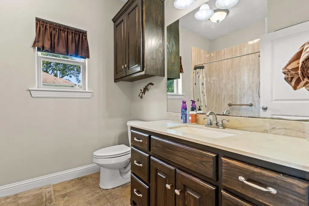 Bathroom featuring a dark wood-finish vanity with a light-colored countertop, an undermount sink, and a framed mirror