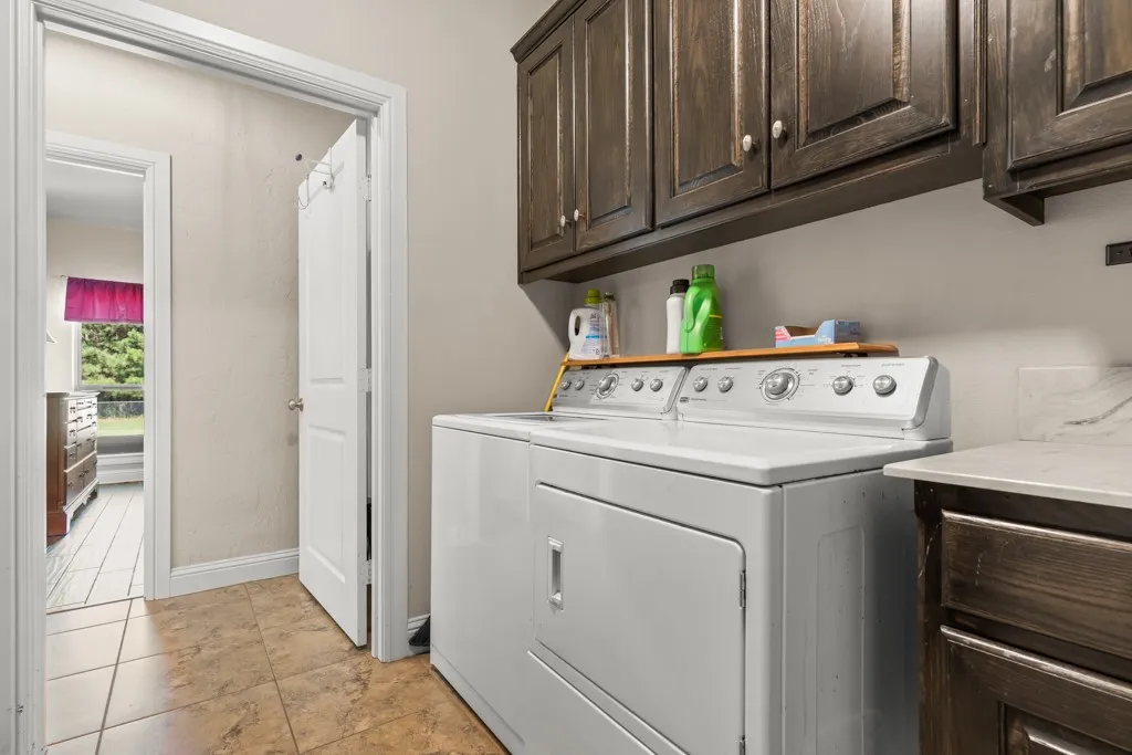 Laundry area featuring dark wood-finish cabinetry, a light-colored countertop, and a tiled floor