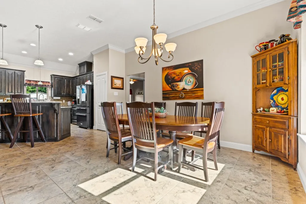 Open-concept kitchen and dining area featuring tile flooring, dark wood-finish cabinetry, a kitchen island with pendant lighting, and a built-in hutch