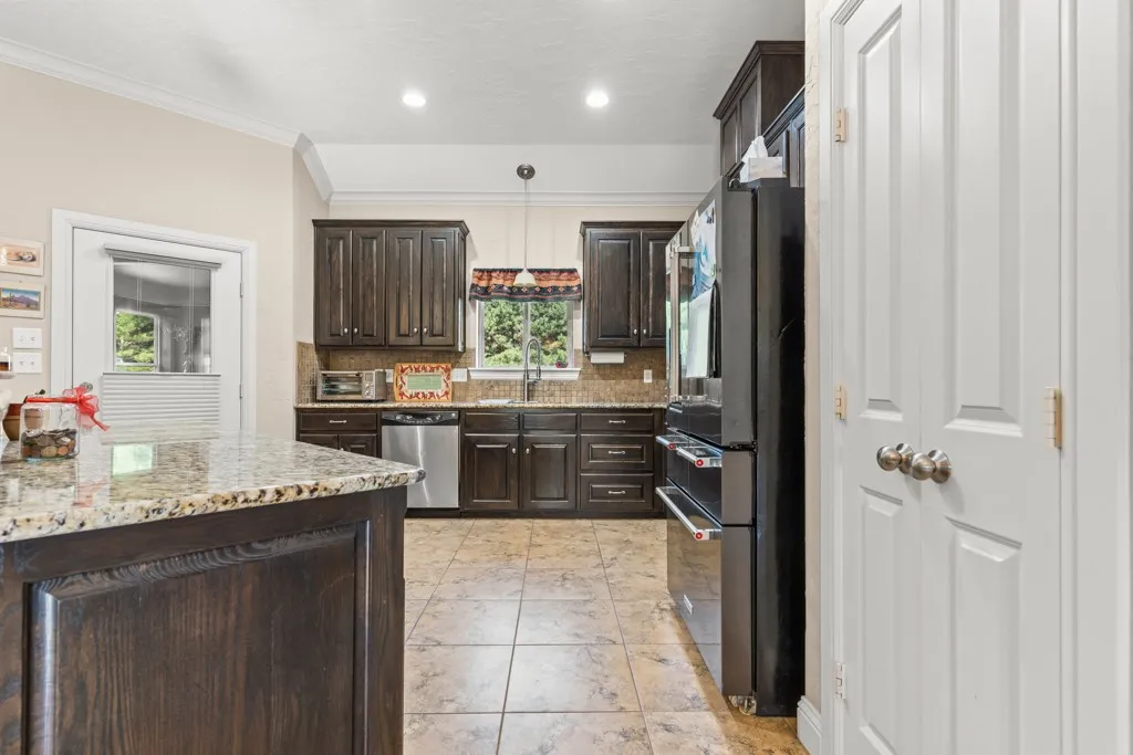 Kitchen featuring dark wood cabinetry, granite countertops, stainless steel appliances, and tile flooring