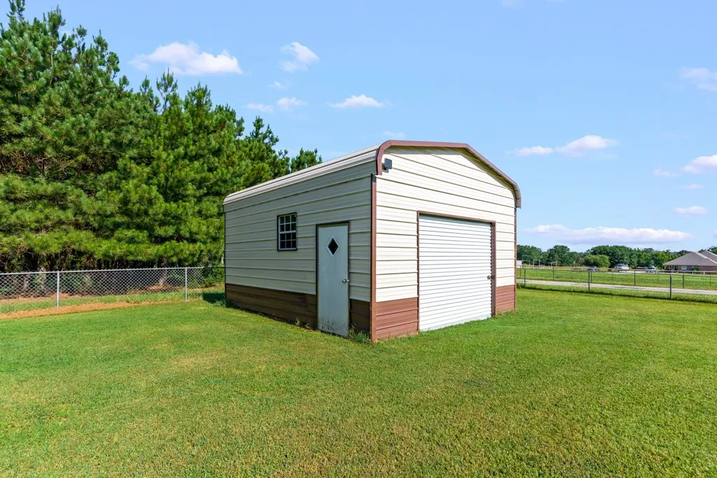 Freestanding metal utility building featuring a roll-up garage door, side entrance door with diamond-shaped window, and a single pane window