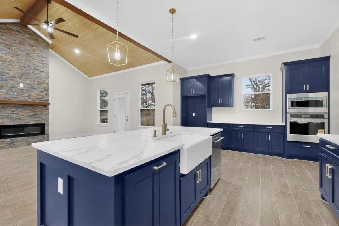 Kitchen island featuring a farmhouse sink, gold-tone faucet, and white countertop