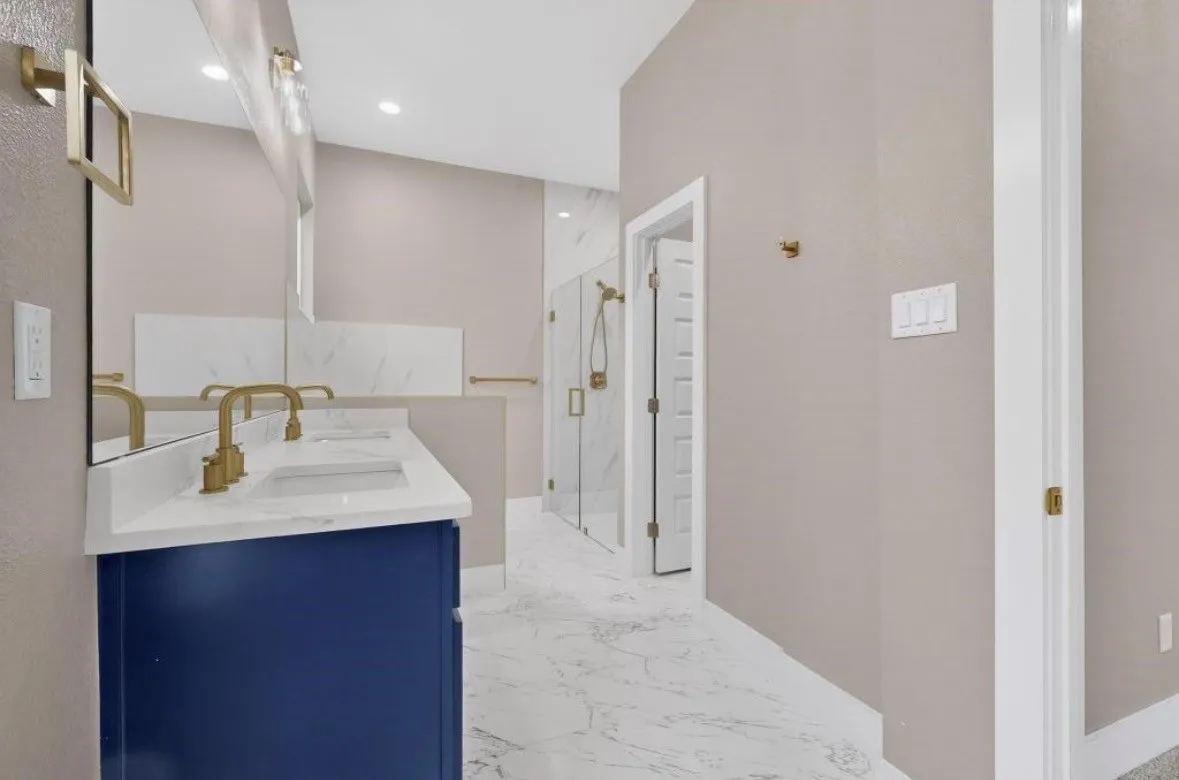 Dual vanity featuring a navy blue cabinet, white countertop, and brass fixtures