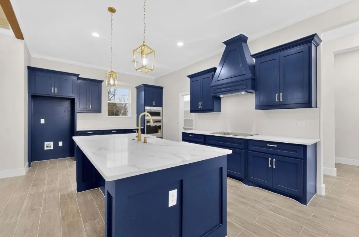 Kitchen featuring a large center island with a stone countertop, deep blue cabinetry, gold-finish fixtures, decorative pendant lighting, and wood-finish flooring