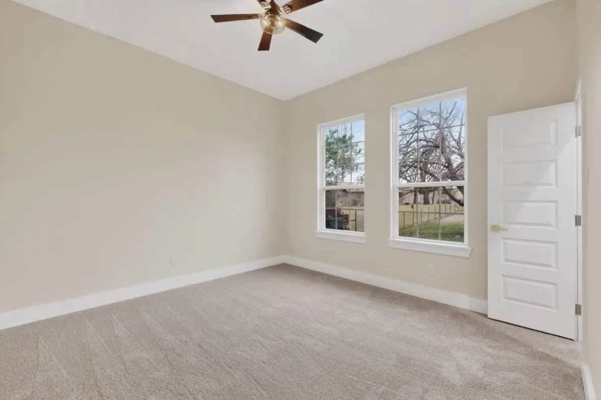 Neutral-toned walls and plush carpet flooring complement two large windows