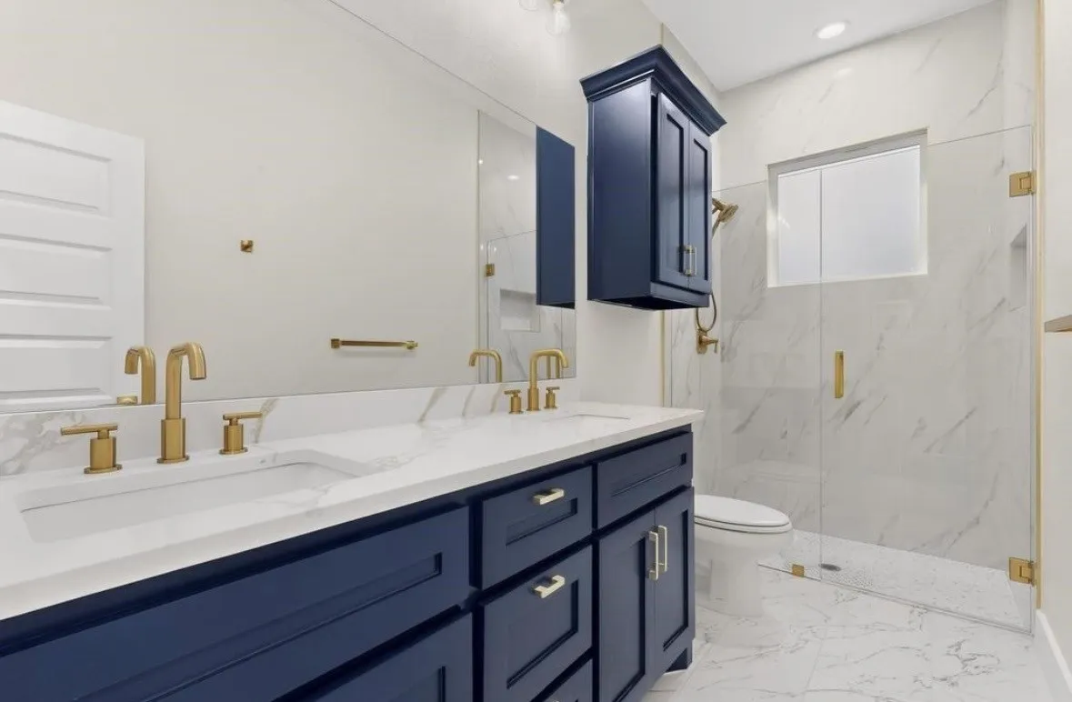 Double vanity with undermount sinks, white countertop, and gold-finish fixtures
