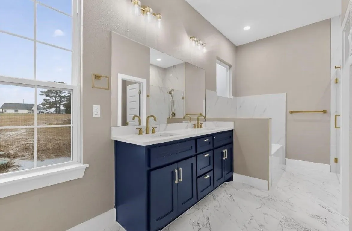 Dual vanity with a white countertop and gold-tone fixtures, deep blue cabinetry, and a full-width mirror