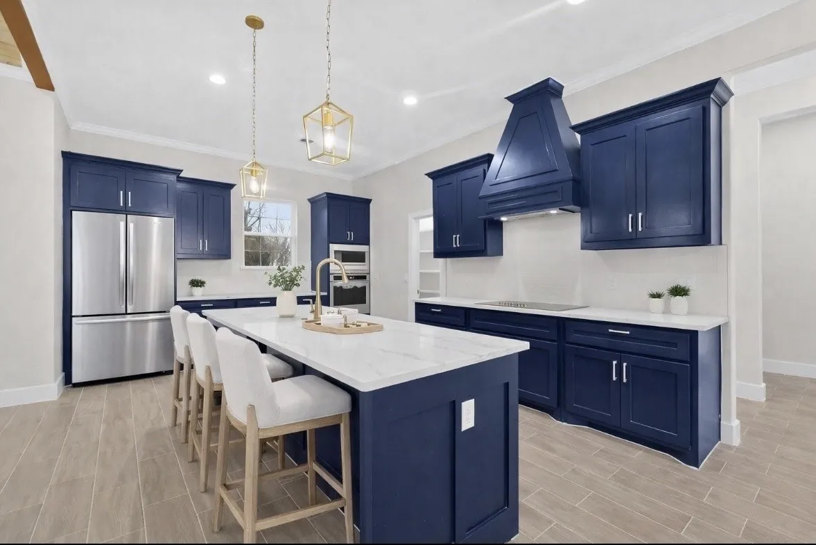 Spacious kitchen featuring deep blue cabinetry, stainless steel appliances, a large center island with a white countertop, and wood-finish flooring