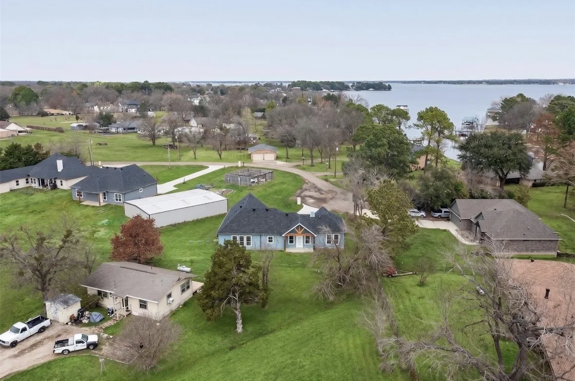 Expansive green landscape featuring multiple residences and a large body of water