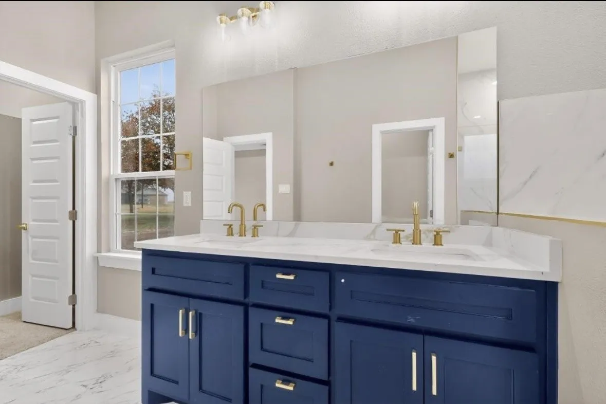 Double vanity with a blue cabinet base, white countertop, and gold-toned fixtures