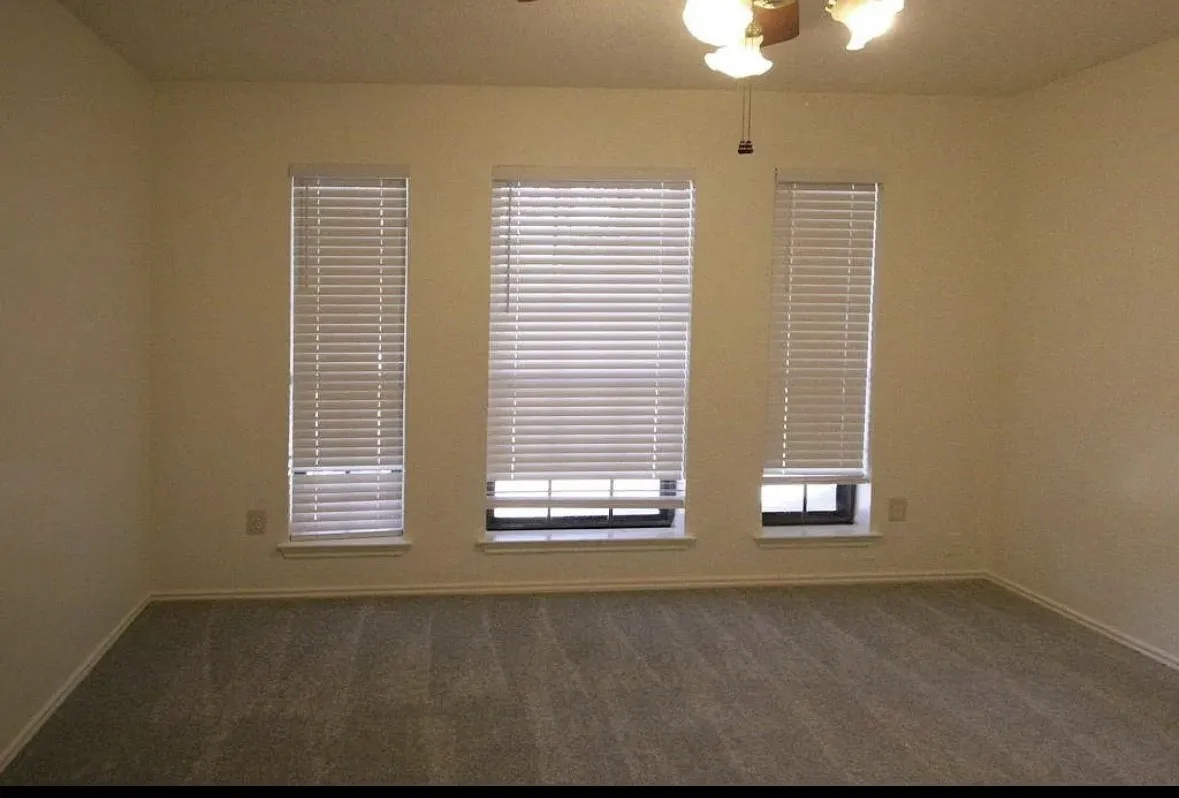 Carpeted empty room featuring baseboards and a ceiling fan