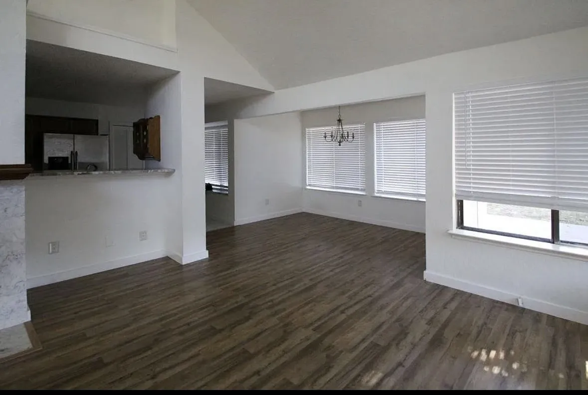 Unfurnished living room featuring a chandelier, lofted ceiling, and dark wood-type flooring