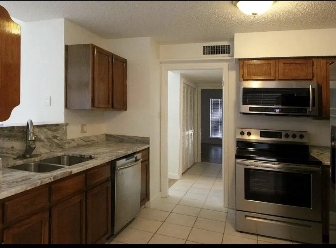 Kitchen featuring stainless steel appliances, light tile patterned floors, and a textured ceiling