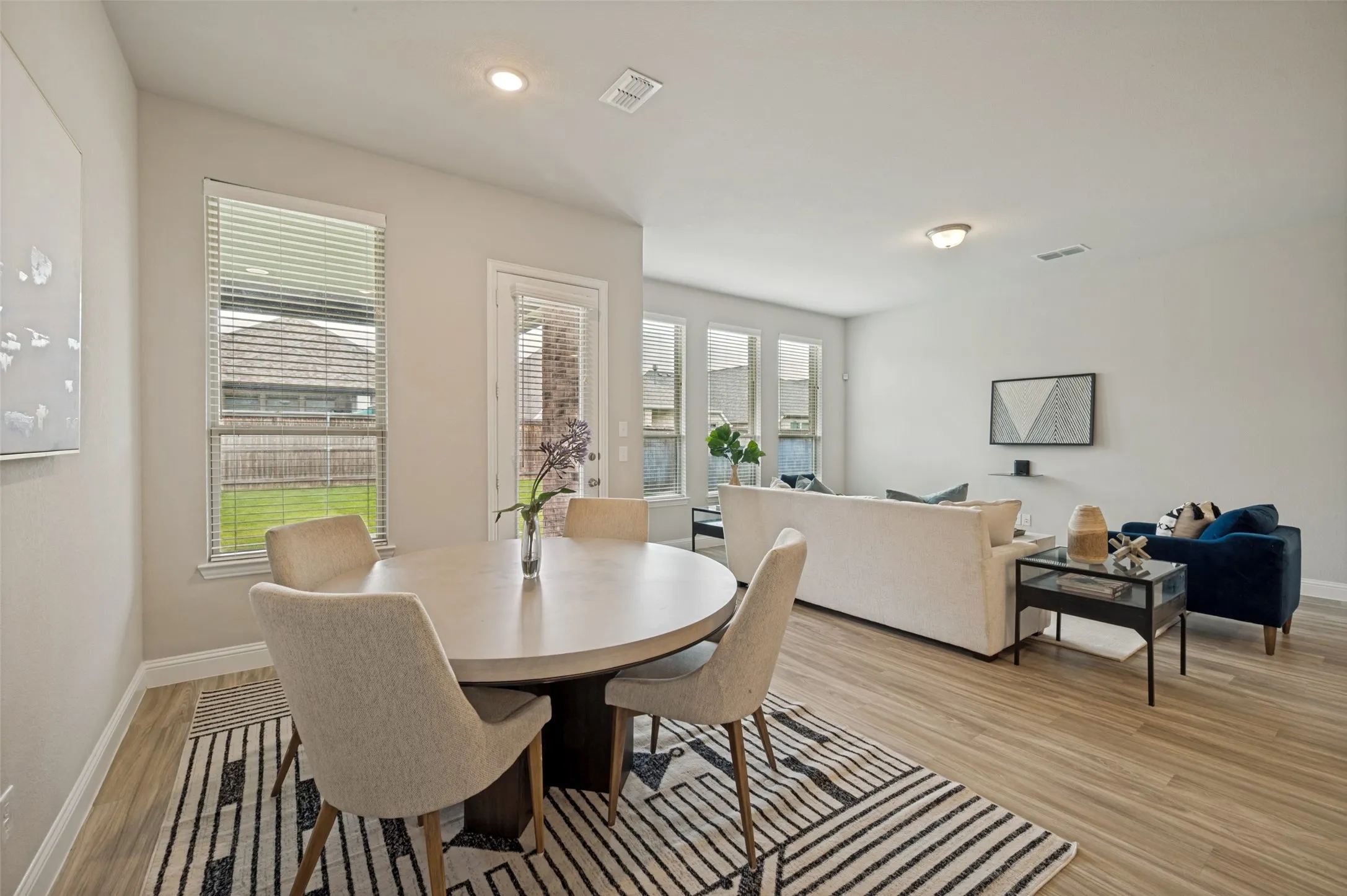Inviting open-concept living and dining spaces designed for both comfort and entertaining. The seamless layout connects the family room, dining area, and kitchen, while large windows provide abundant natural light and views of the backyard. A perfect setting for gathering with family and