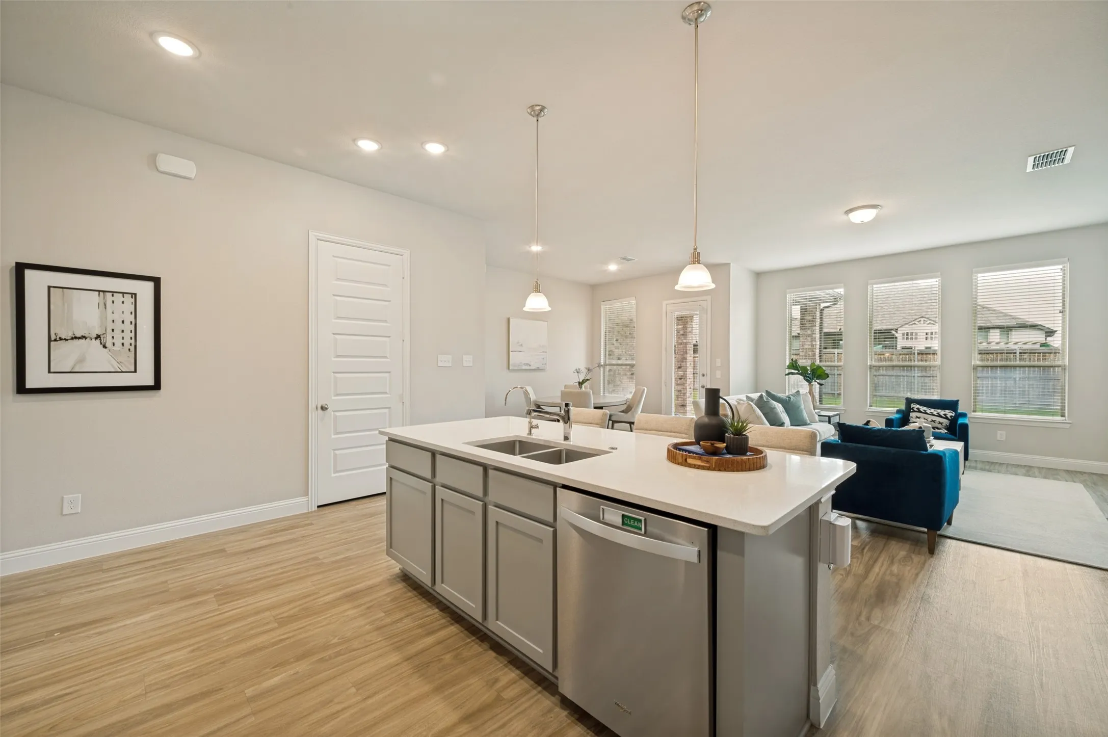 Beautiful open-concept kitchen featuring a large center island with seating, quartz countertops, stainless steel appliances, abundant cabinet storage, and a gas range. Designed for both everyday living and entertaining, the kitchen flows seamlessly into the spacious living and dining areas.