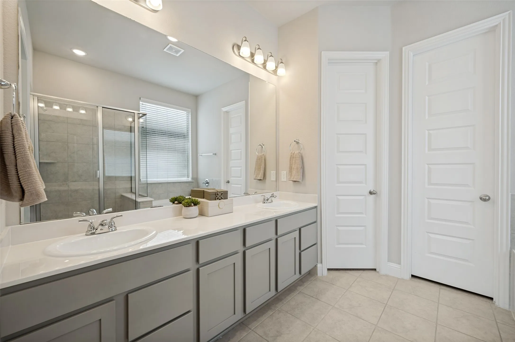 Spa-inspired primary bathroom featuring a dual-sink vanity with abundant counter space, oversized mirror, walk-in shower with glass enclosure, and a soaking tub for ultimate relaxation. Thoughtfully designed with ample storage and modern finishes, this private retreat offers both comfort and functionality.