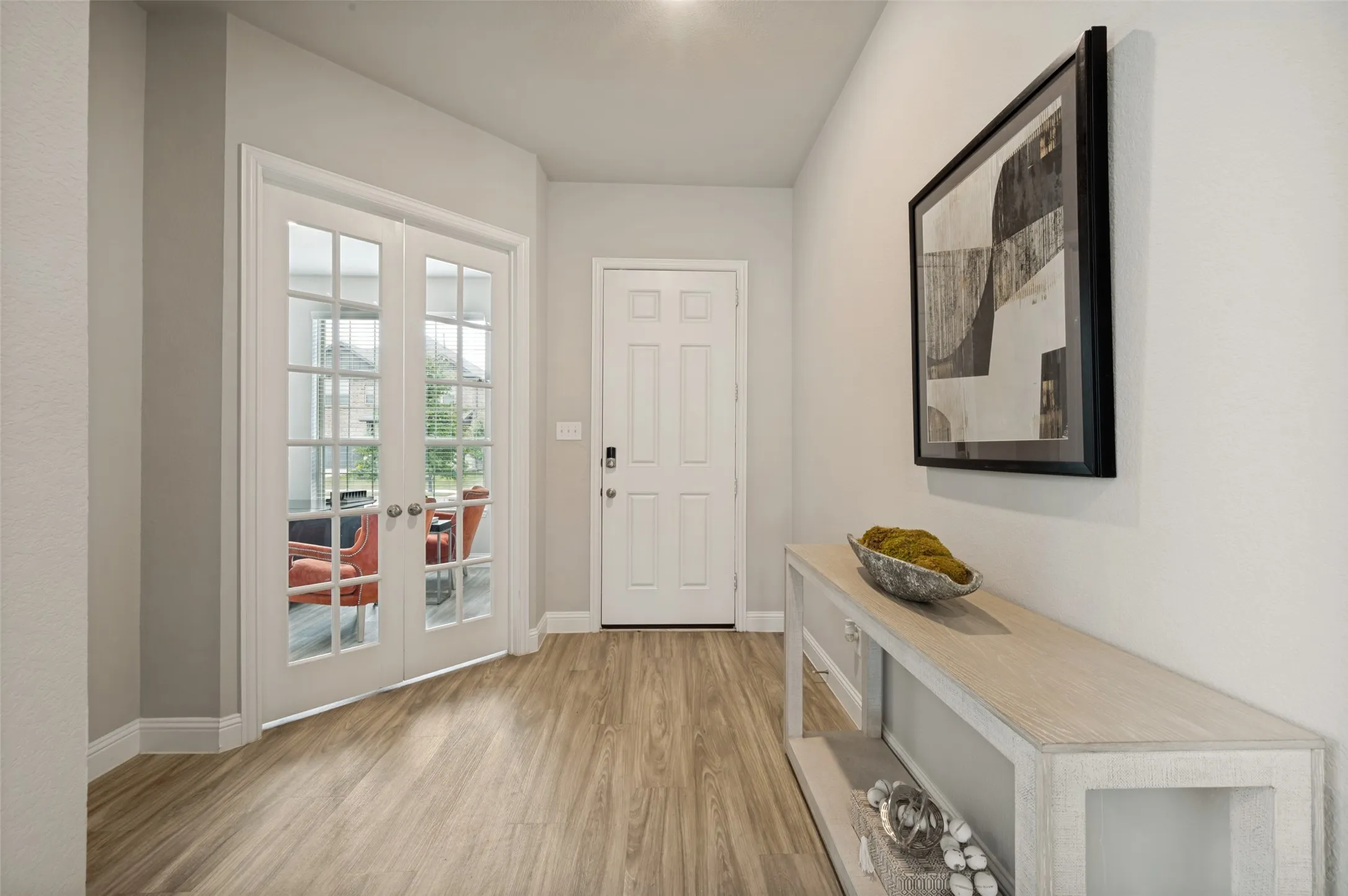 The welcoming foyer showcases beautiful wood-look flooring, neutral designer finishes, and an open-concept layout that creates an inviting flow throughout the home. Just off the entry, elegant French doors lead to the private home office, while the spacious hallway opens seamlessly into the main living and entertaining areas.