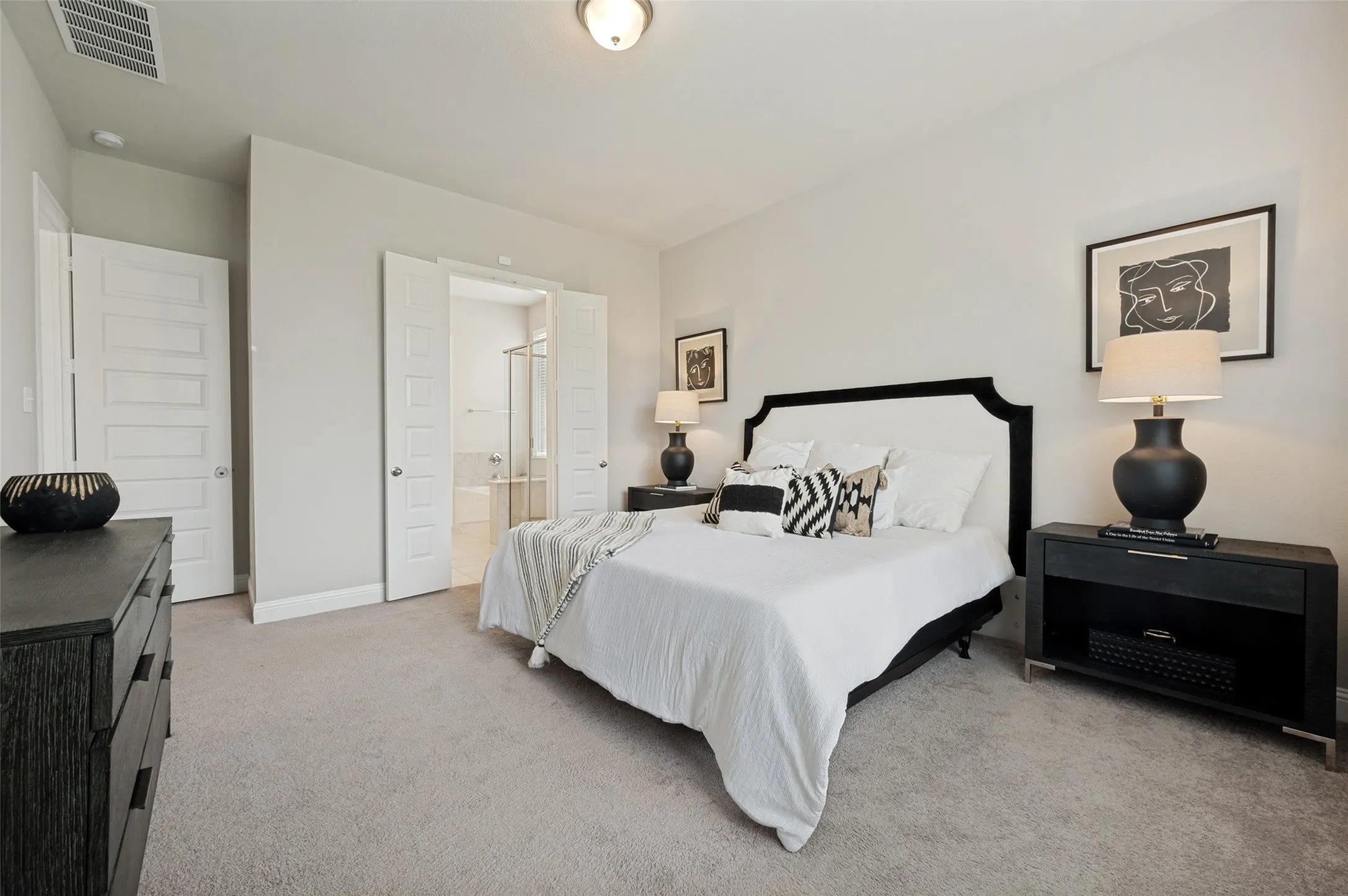 Relax and unwind in the spacious primary suite featuring plush carpeting, neutral designer finishes, and a private ensuite bath. The generous layout offers ample room for a king-sized bed and additional furnishings, creating a comfortable retreat to start and end your day.