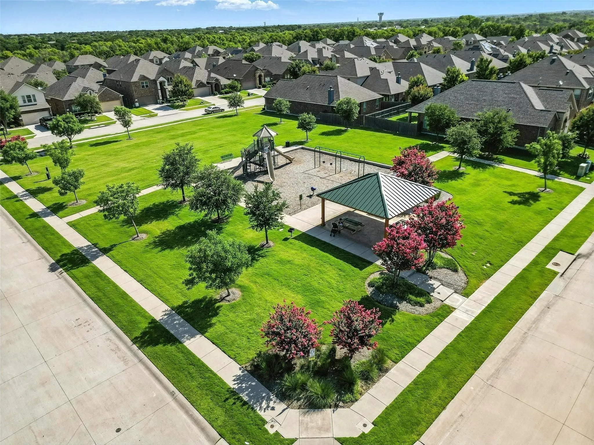 Expansive community green space featuring a playground, covered picnic area, and mature trees